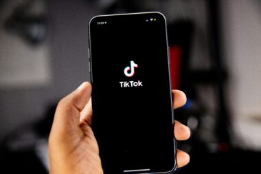 Dłoń trzymająca smartfon z ekranem startowym aplikacji TikTok