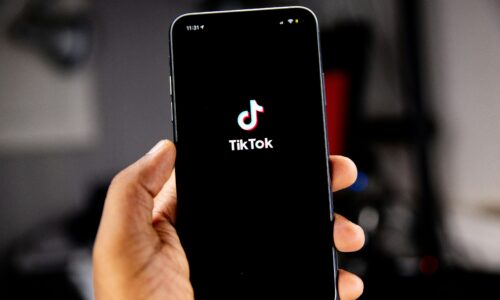 Dłoń trzymająca smartfon z ekranem startowym aplikacji TikTok