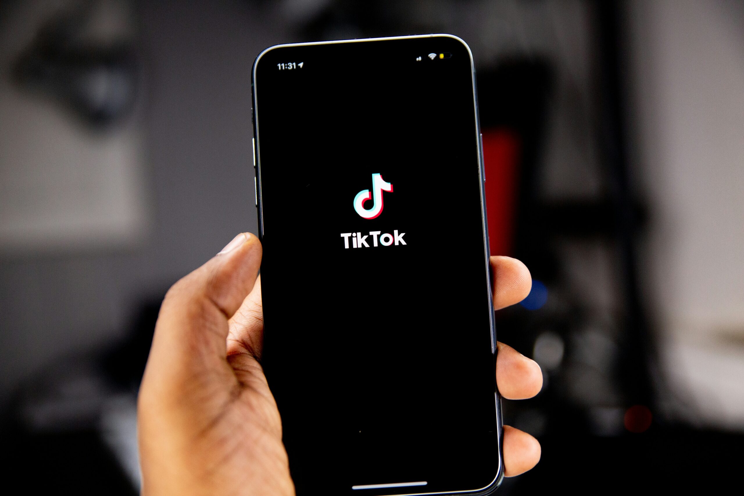 solen-feyissa-Yaw9mfG9QfQ-unsplash Dłoń trzymająca smartfon z ekranem startowym aplikacji TikTok