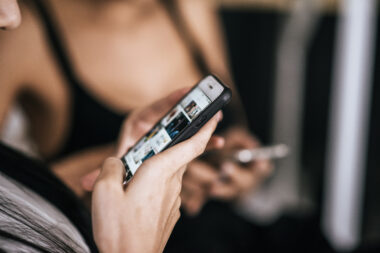 Kobieta trzymająca smartfon i przewijająca treści w aplikacji społecznościowej z bliska