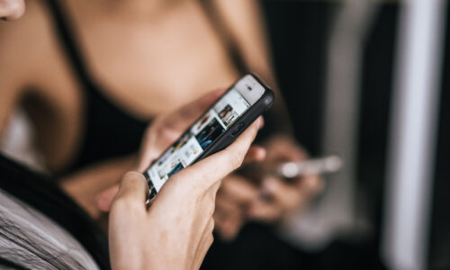 Kobieta trzymająca smartfon i przewijająca treści w aplikacji społecznościowej z bliska